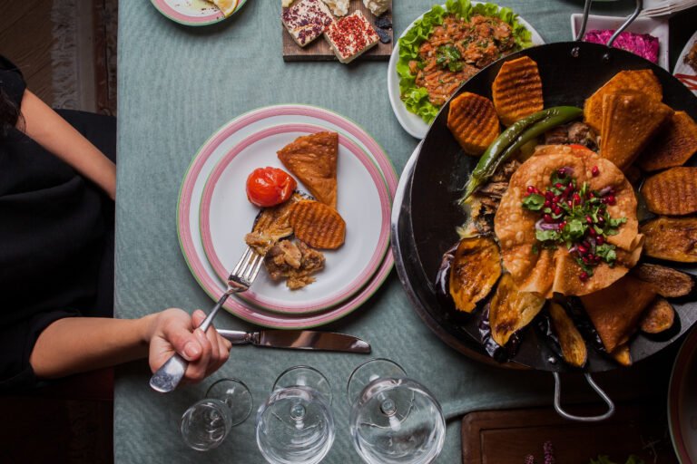 close up meat with baked potatoes, eggplant, tomato, pepper and decorated with pomegranate in a plate on served table